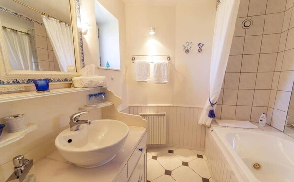 Un baño con un lavamanos grande, una bañera, una ducha y un espejo.