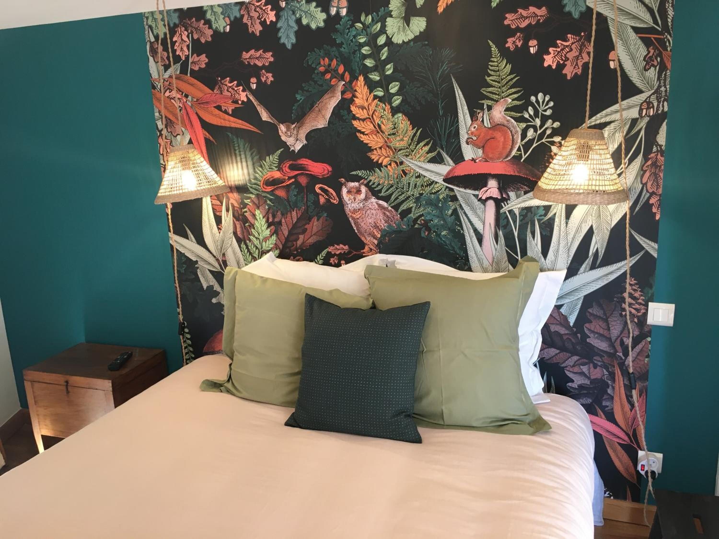 Un lit avec une tête de lit de couleur turquoise, une couette blanche et trois oreillers. Deux lampes murales sont fixées de chaque côté du lit.