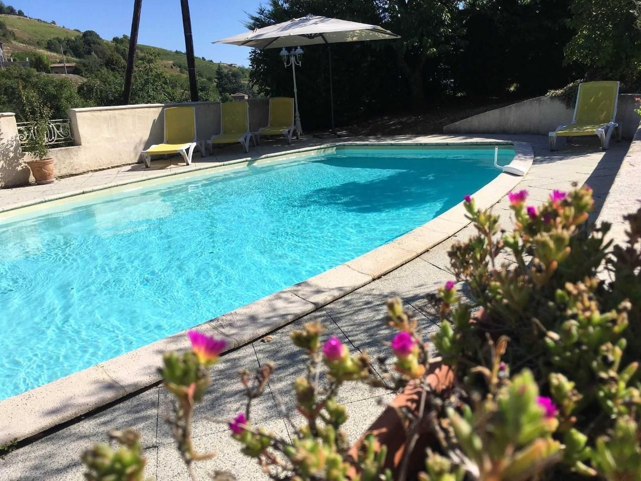 A swimming pool with lounge chairs and an umbrella.