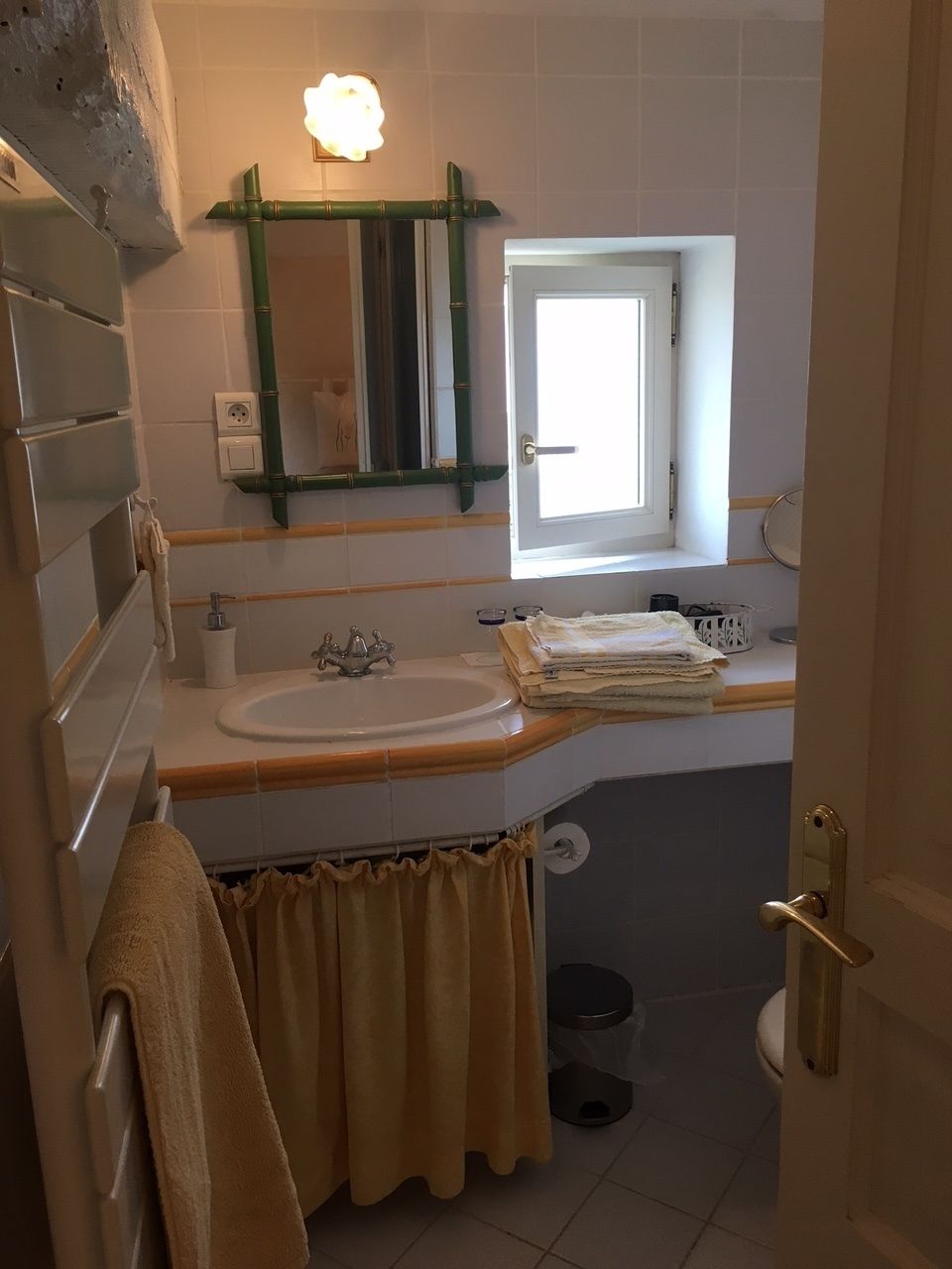 A bathroom with a sink, mirror, window, and toilet.