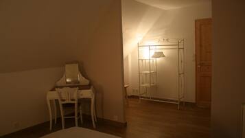 Ein Zimmer mit einem Bett, einem Schreibtisch mit Stuhl, einer Holztür und einem Metallregal mit Ablagen.