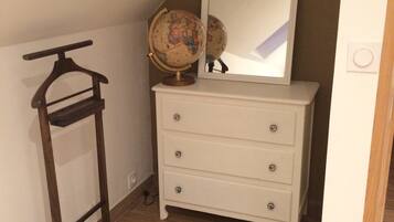 Une pièce avec une commode blanche, un cintre en bois et un globe posé sur le dessus.