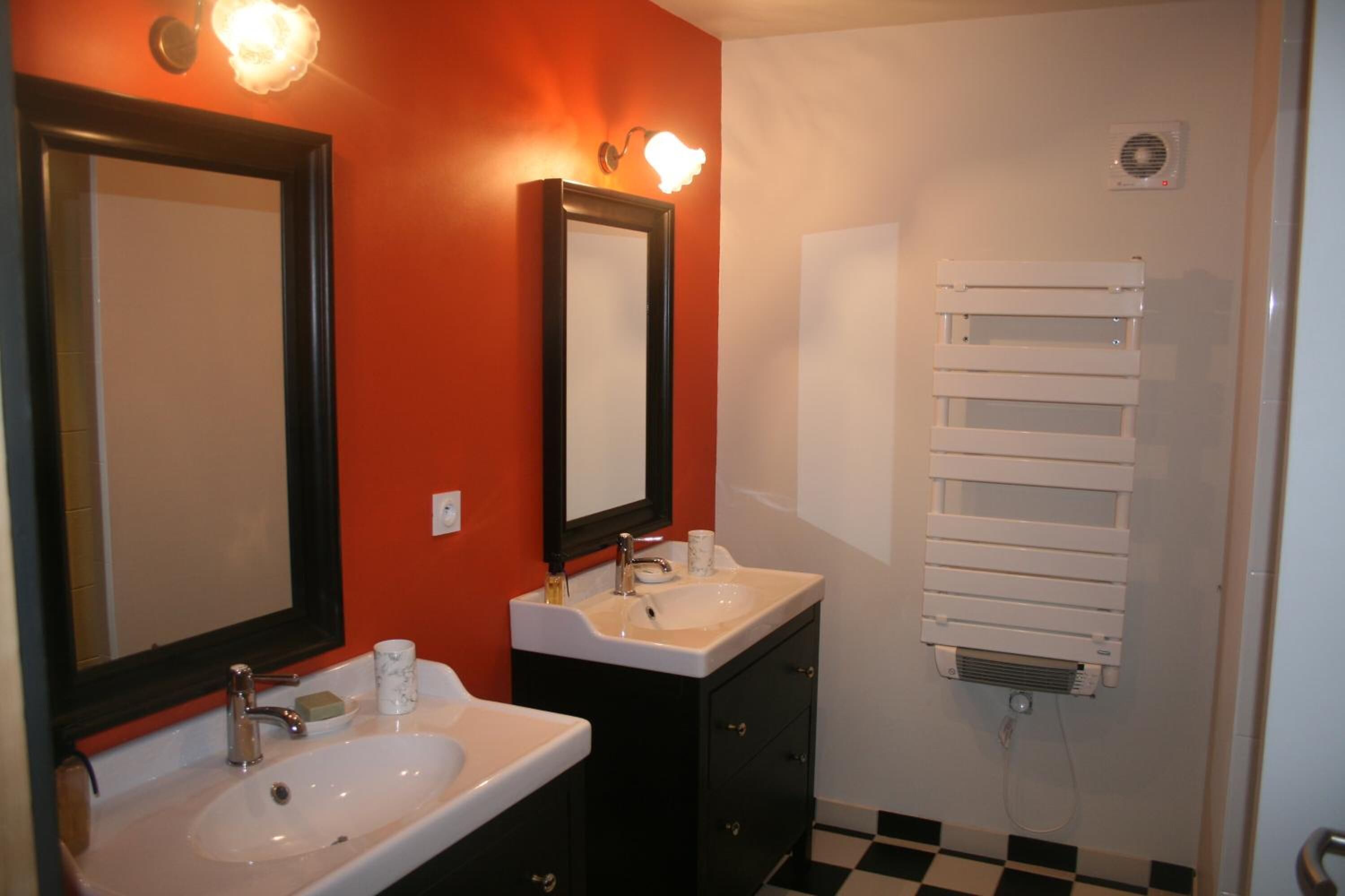 A bathroom with two sinks, a mirror, a towel rack, and a heater.