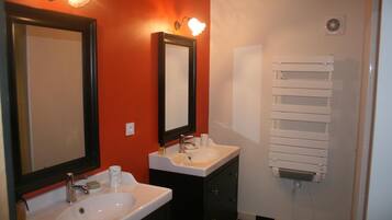 A bathroom with two sinks, a mirror, a towel rack, and a heater.