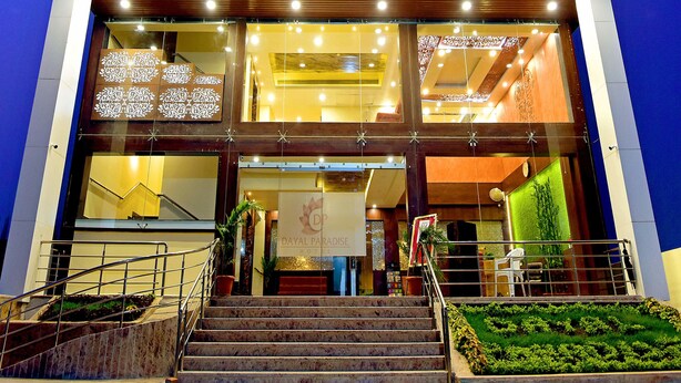 Un hôtel moderne avec une enseigne bien visible indiquant « DAYAL PARADISE HOTEL » et une entrée bien éclairée.