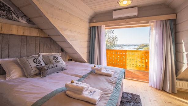 Une chambre avec un grand lit, deux tables de chevet, une fenêtre avec des rideaux et une vue sur l’extérieur.