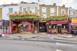 A pub with a red facade and flower boxes on the upper floor.