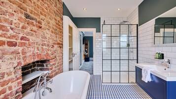 Ein modernes Badezimmer mit Backsteinwand, freistehender Badewanne, begehbarer Dusche und blau-weiß kariertem Boden.