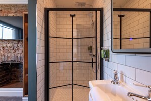 A modern bathroom with a glass-enclosed shower, a white sink, and a large mirror.