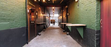 A narrow alleyway with a brick wall on one side and a green wall on the other, leading to a door labeled "The Half Crown."