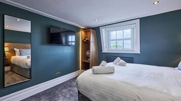 A bedroom with a large bed, a walk-in closet, a television, and a window with a view.