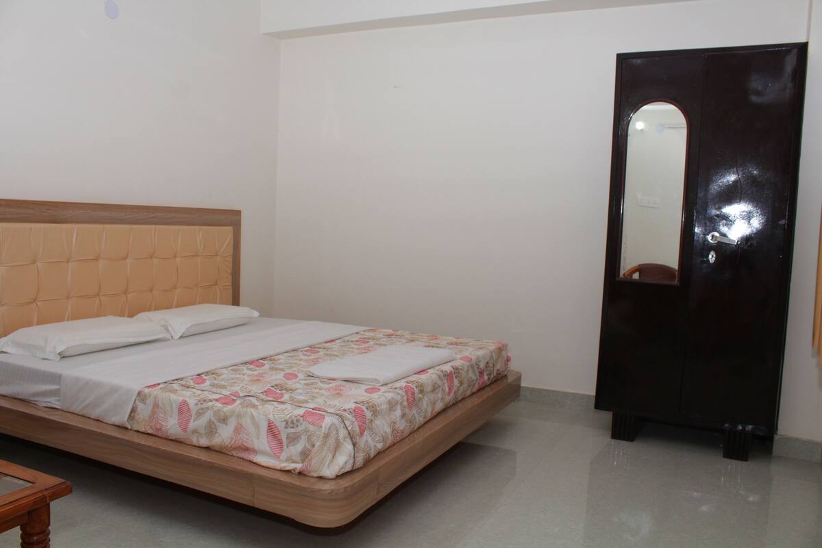 A bedroom with a bed, a wooden headboard, a wardrobe, and a mirror.