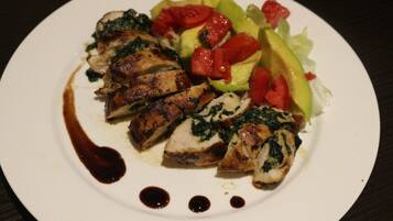 Un plato de pollo a la parrilla con vegetales y salsa oscura.