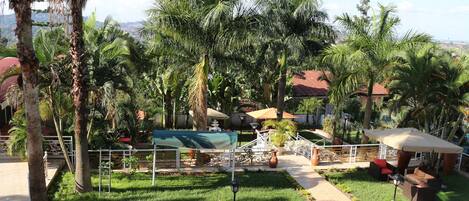 A lush garden with palm trees, a gazebo, and outdoor seating.