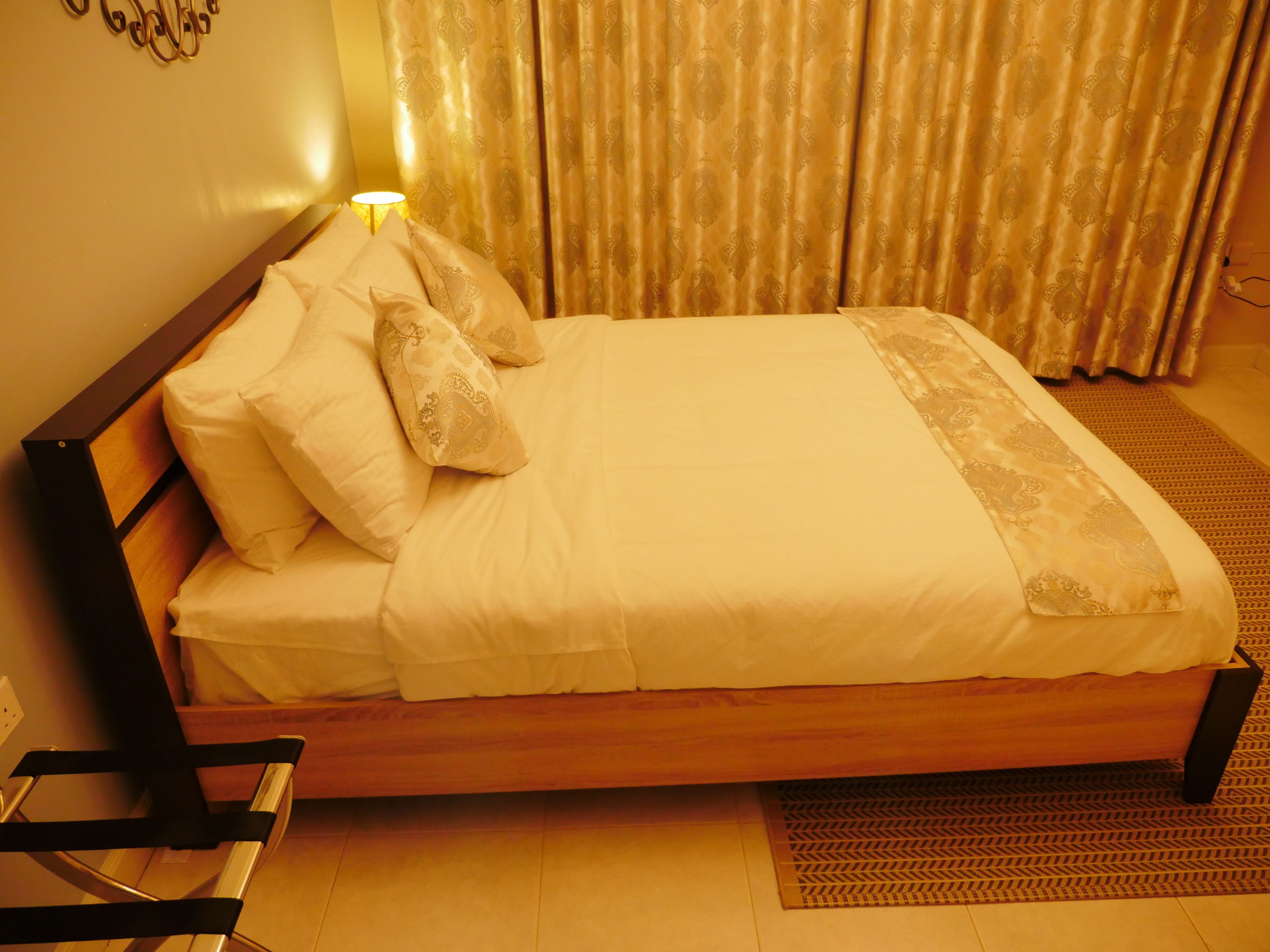 A neatly made bed with a wooden frame, white bedding, and decorative pillows.
