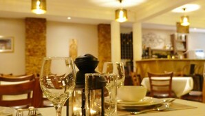 A dining table set with wine glasses, a bowl, and cutlery in a well-lit restaurant interior. - Ivory Castle Boutique Hotel (Kampala)