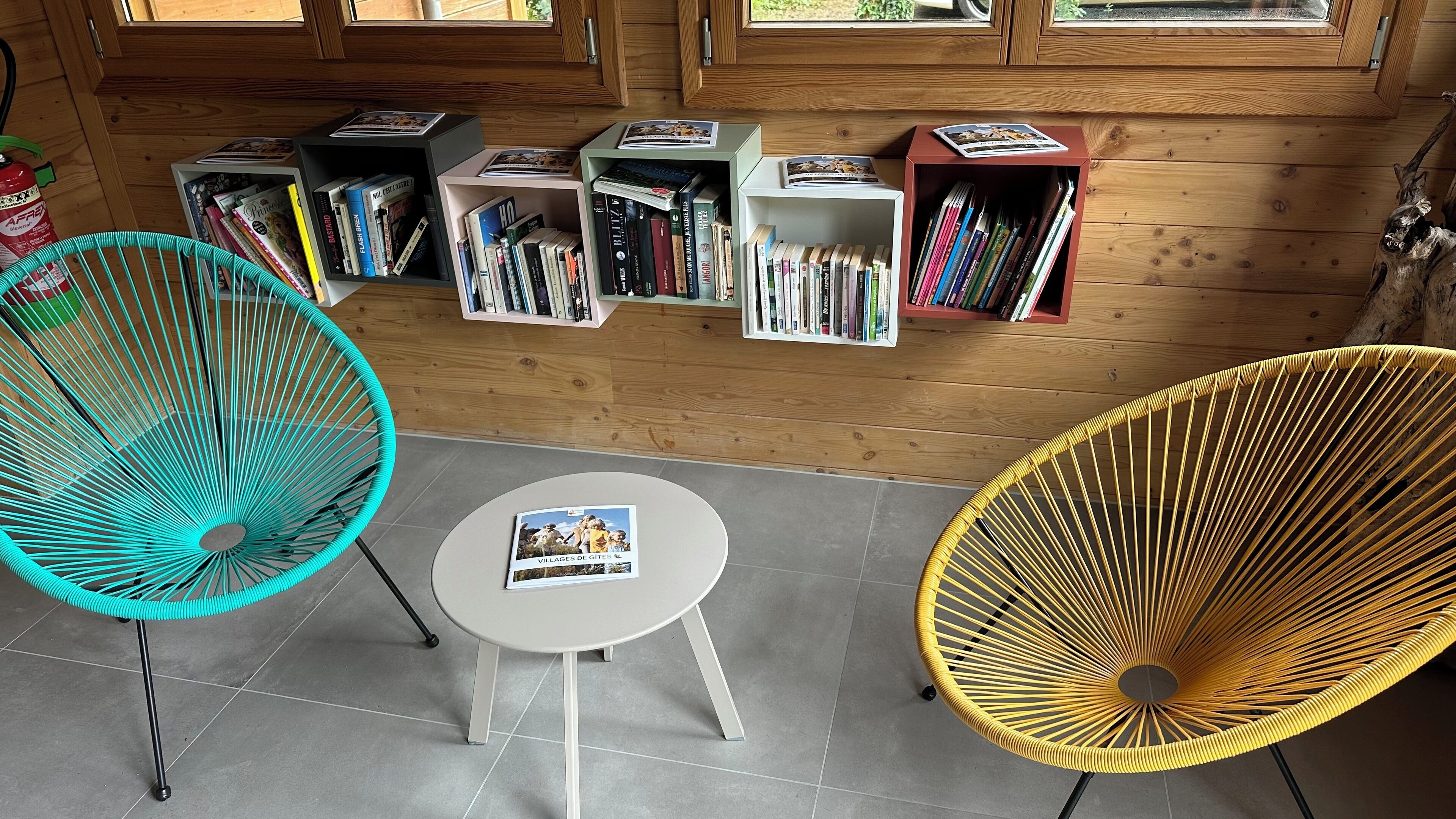 A cozy reading area with two chairs, a small table, and a bookshelf filled with books.