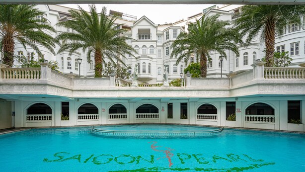 A pool with 'SAIGON PEARL' written in the water, surrounded by a white building with arched windows and palm trees. - Aviva Saigon Pearl (Ho Chi Minh City)