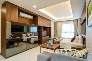 Una habitación de hotel moderna con una cama grande, un sofá, una mesa de centro, un televisor y un armario.