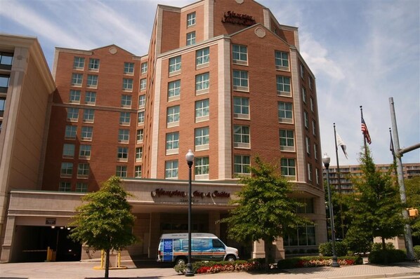 A Hampton Inn hotel with a brick facade, multiple windows, and a parking lot with a van. - Hampton Inn & Suites (Arlington)