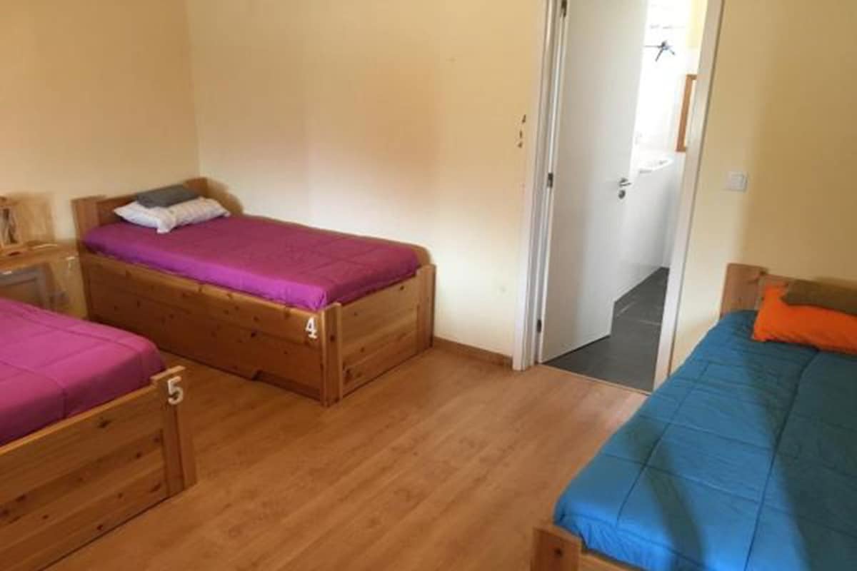 A room with three wooden beds, each with a different colored bedspread.