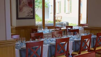 Un espace repas avec des tables dressées pour le repas, des chaises en bois et une vue sur la rue.