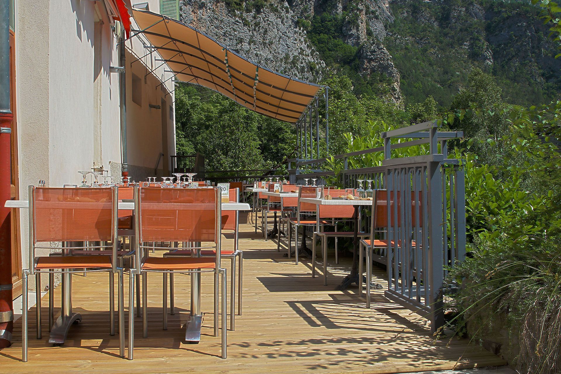 An outdoor dining area with tables and chairs, a wooden deck, and a mountainous backdrop.