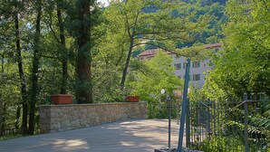 A wooden pathway leading through a lush green area with stone walls and metal fencing.