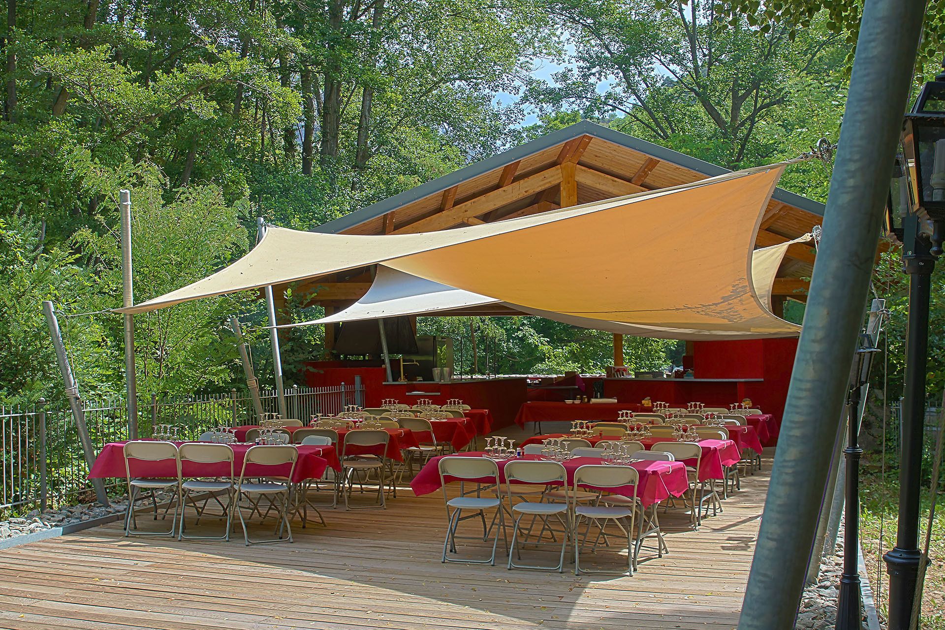 Un área de comedor al aire libre con mesas y sillas, cubierta por un toldo grande.