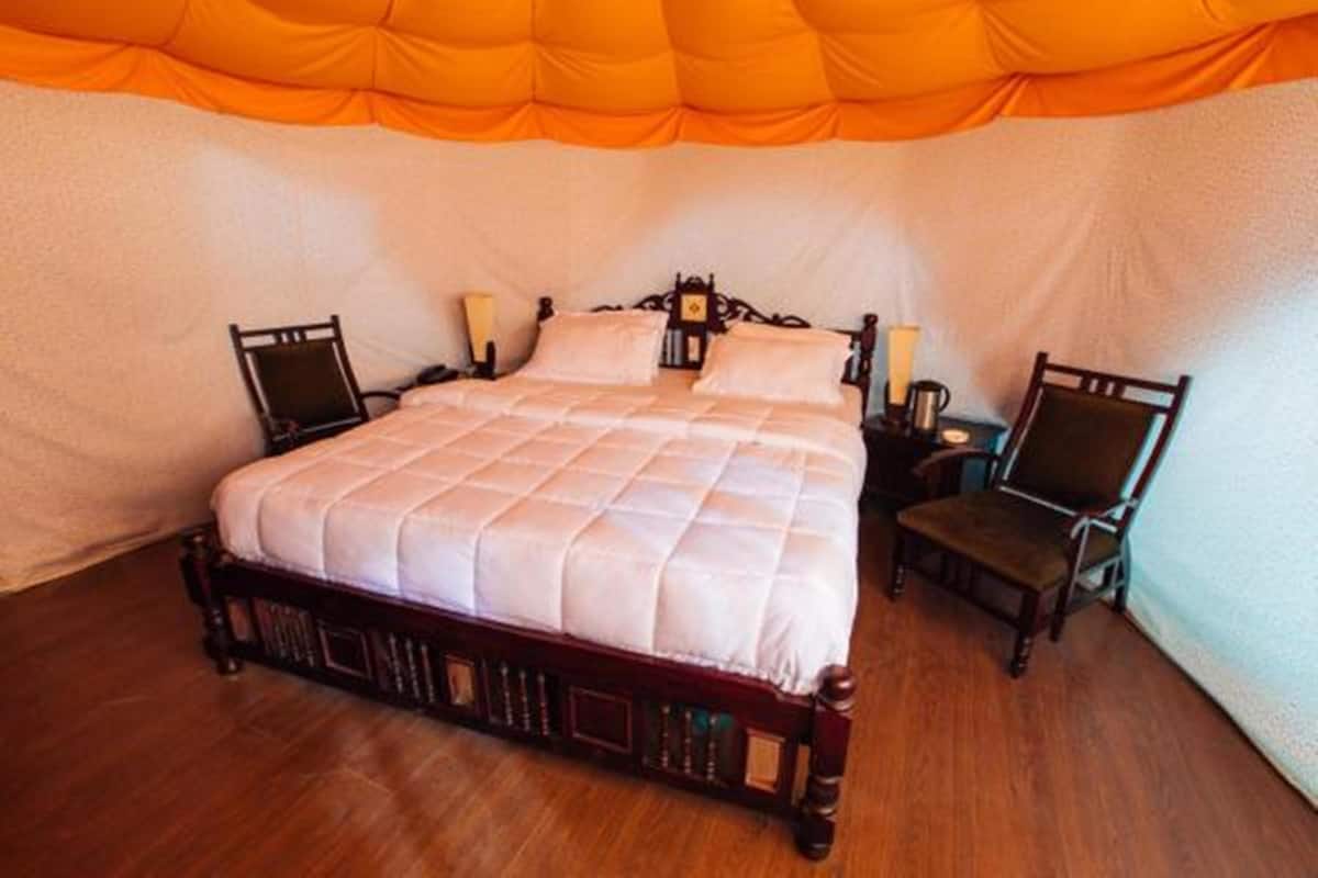 A bed with a quilted white cover, two bedside tables with lamps, and two chairs.