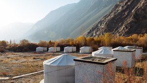 A row of white tents with flat roofs, set against a mountainous backdrop. - Hunder Sarai (Leh)