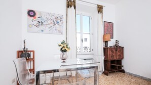 A dining area with a glass table and chairs, a vase with flowers, and a wooden cabinet with decorative items. - Domus Linda (Rome)