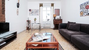 A living room with a sofa, coffee table, TV, and a dining area with chairs and a table. - Domus Linda (Rome)