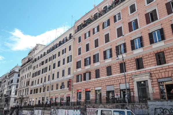 A row of multi-story buildings with uniform architectural style, featuring balconies, windows, and signage.
