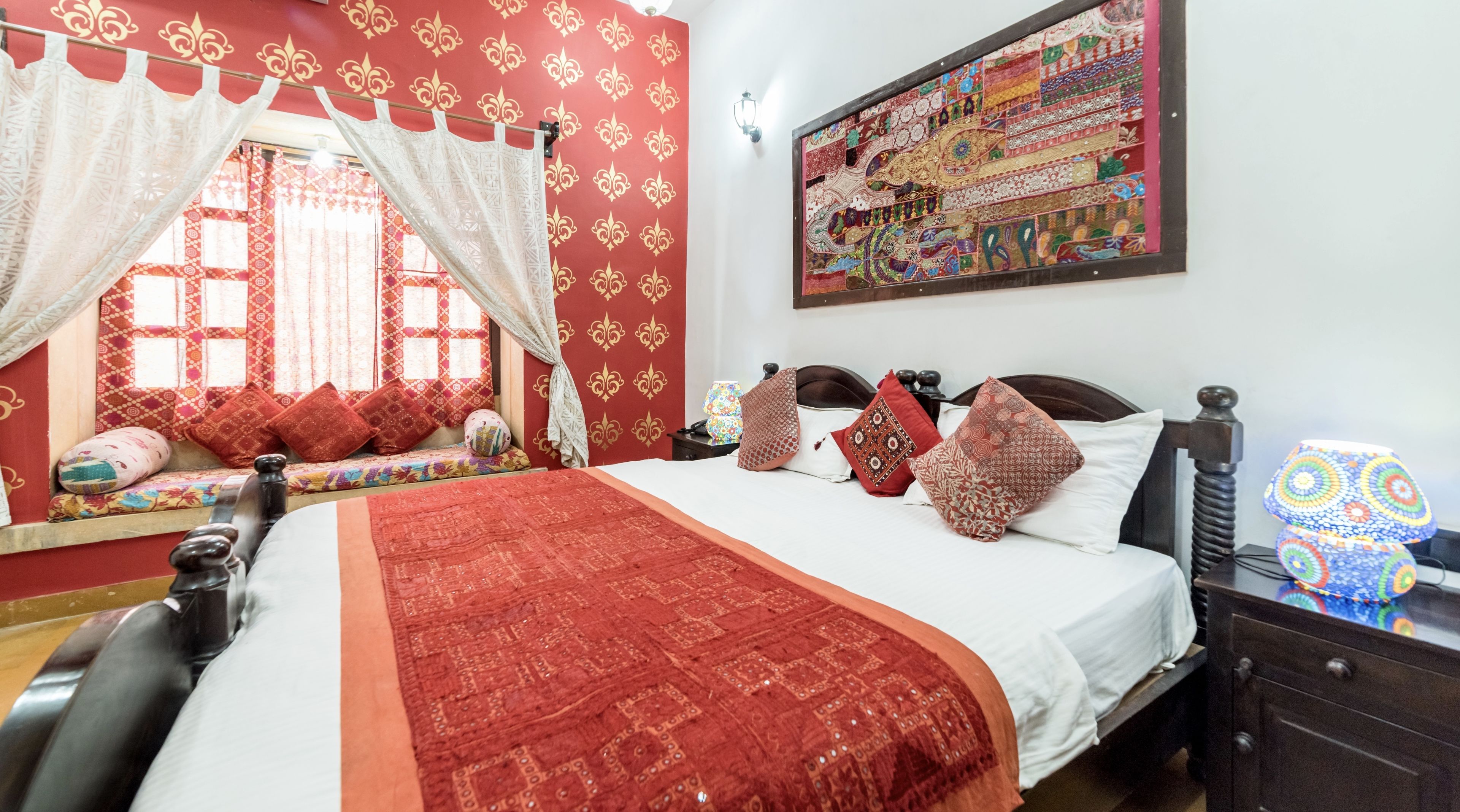 Una stanza con un letto, una finestra con tende, un muro con motivo decorativo e un quadro.