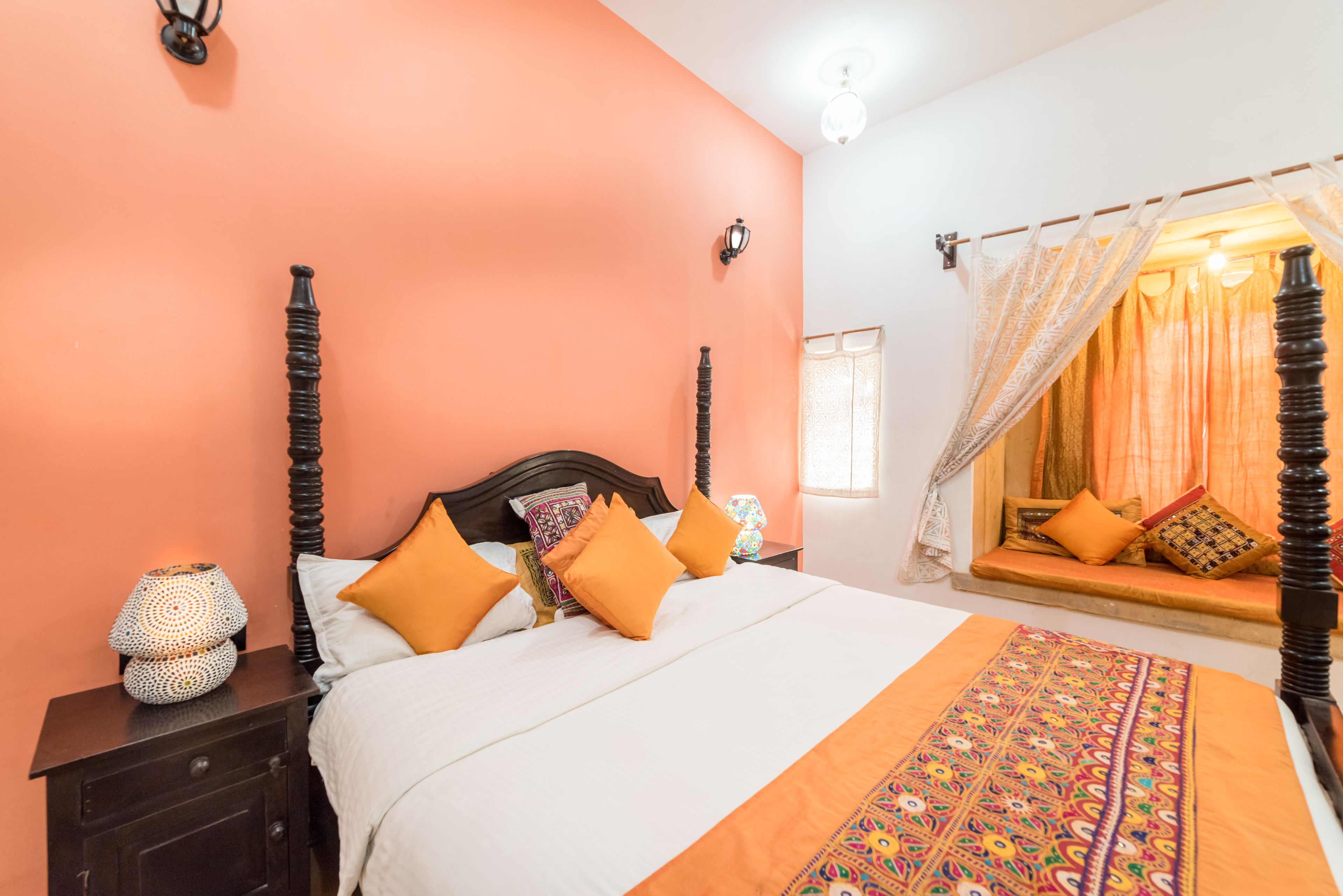 A bedroom with a bed, nightstands, a window with a view, and a decorative curtain.