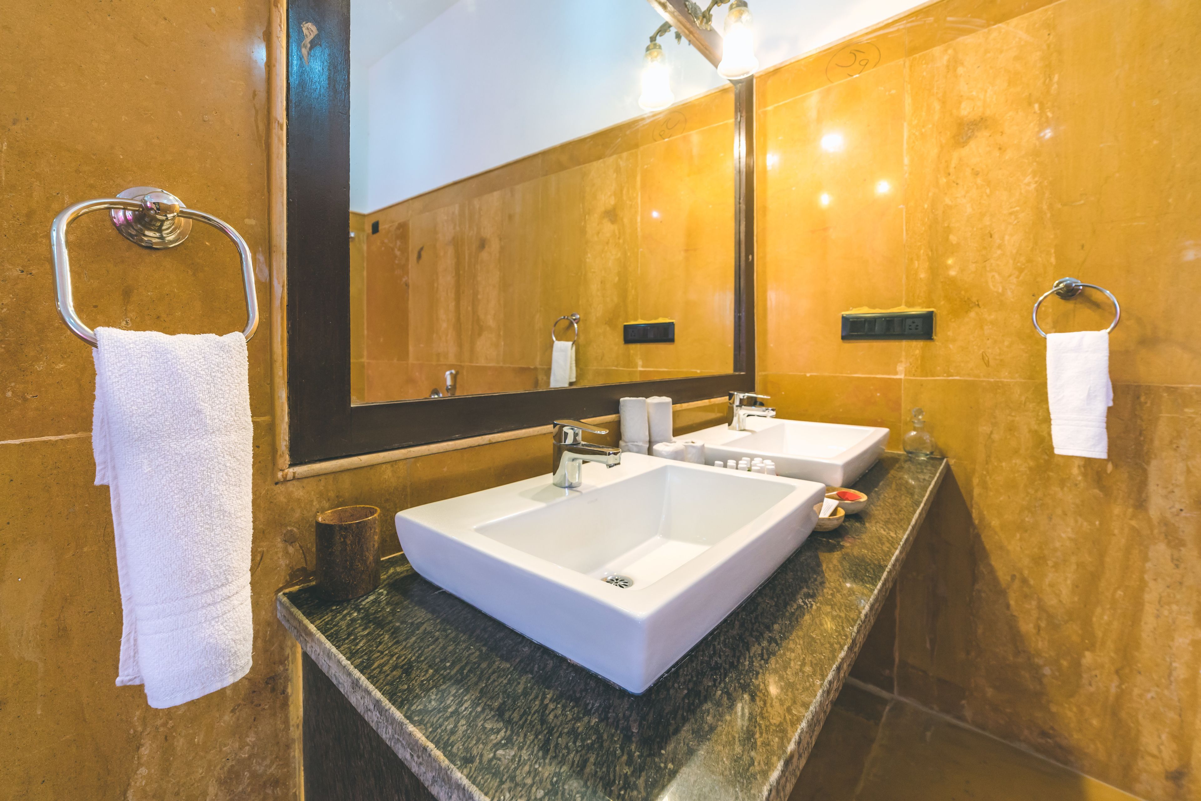 Une salle de bain avec un grand miroir, deux lavabos et un porte-serviettes.