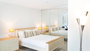 Un dormitorio moderno con una cama de madera, lámparas de noche, un espejo y una mesita de noche.