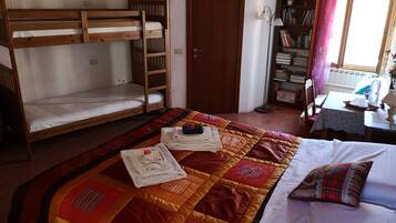 Une chambre de dortoir avec des lits superposés, un espace d’étude avec des étagères et une table à manger.