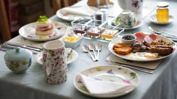 Une table de petit-déjeuner avec différents plats, couverts et une tasse ornée de motifs floraux.