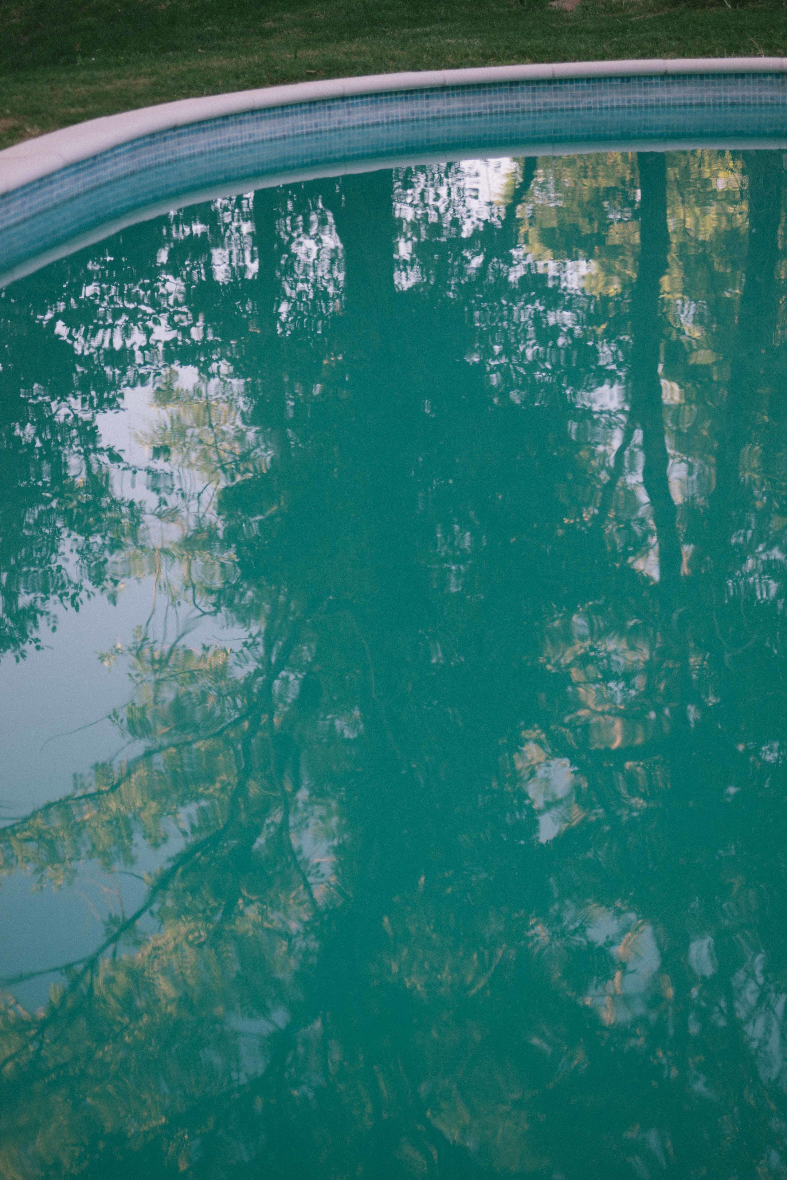 Una piscina con una vista despejada de árboles reflejados en el agua.