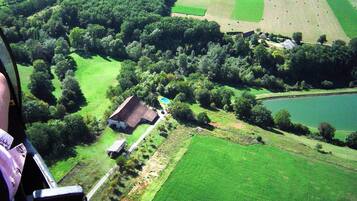 An aerial view of a rural landscape with fields, a small house, and a body of water.