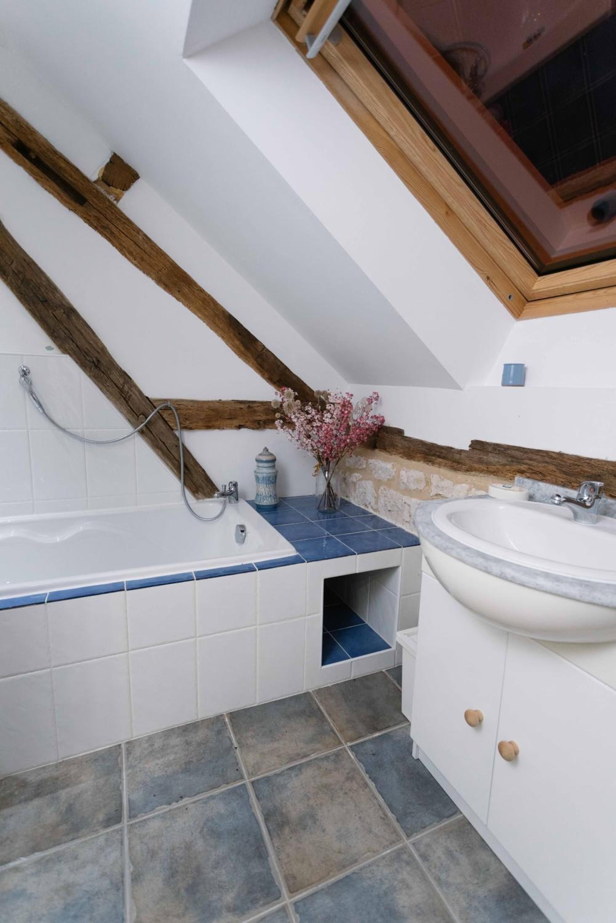 A bathroom with a bathtub, a sink, and a window.