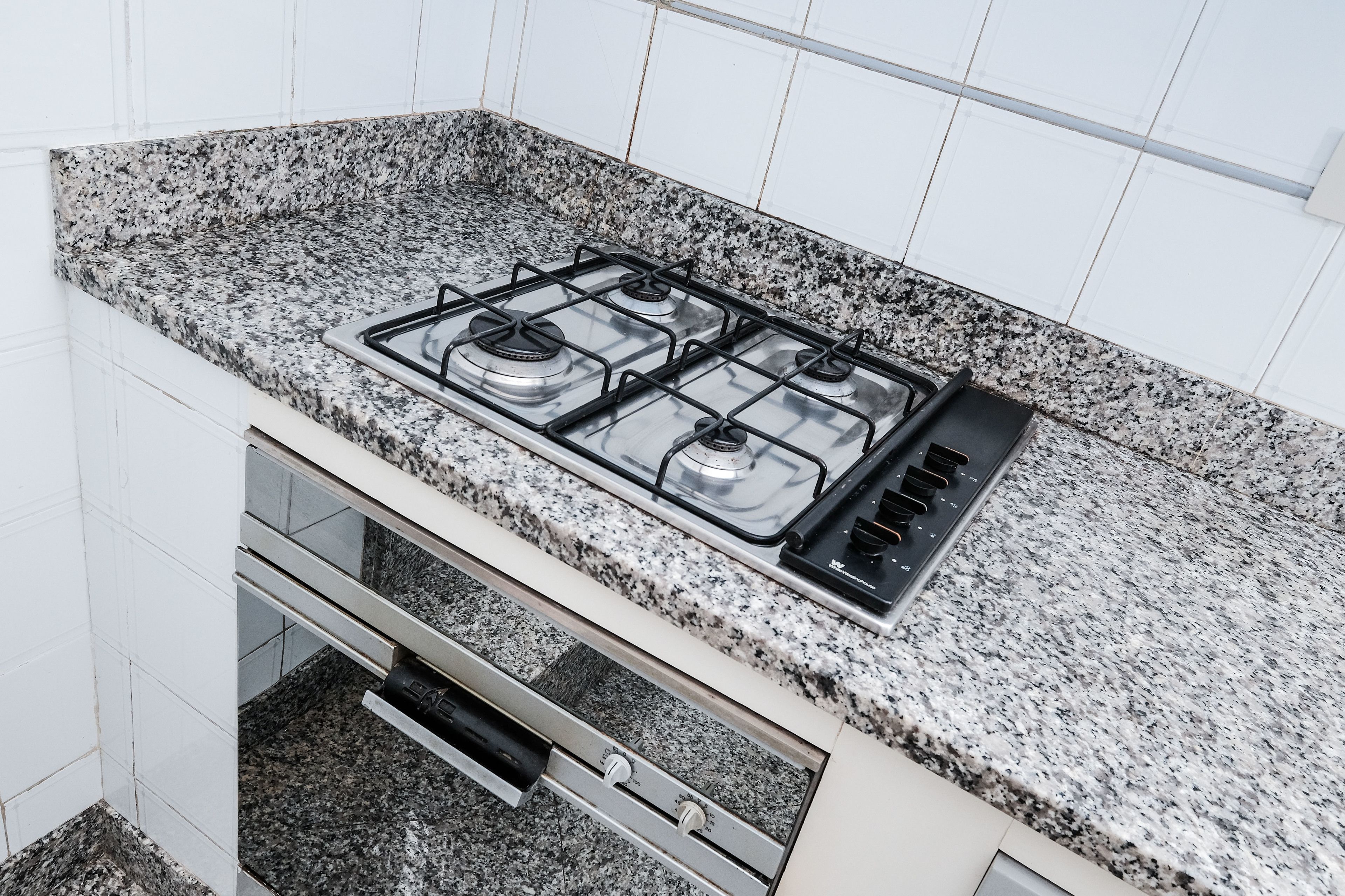 Eine Küche mit Granitarbeitsplatte, einem Gasherd und einem Edelstahlbackofen.