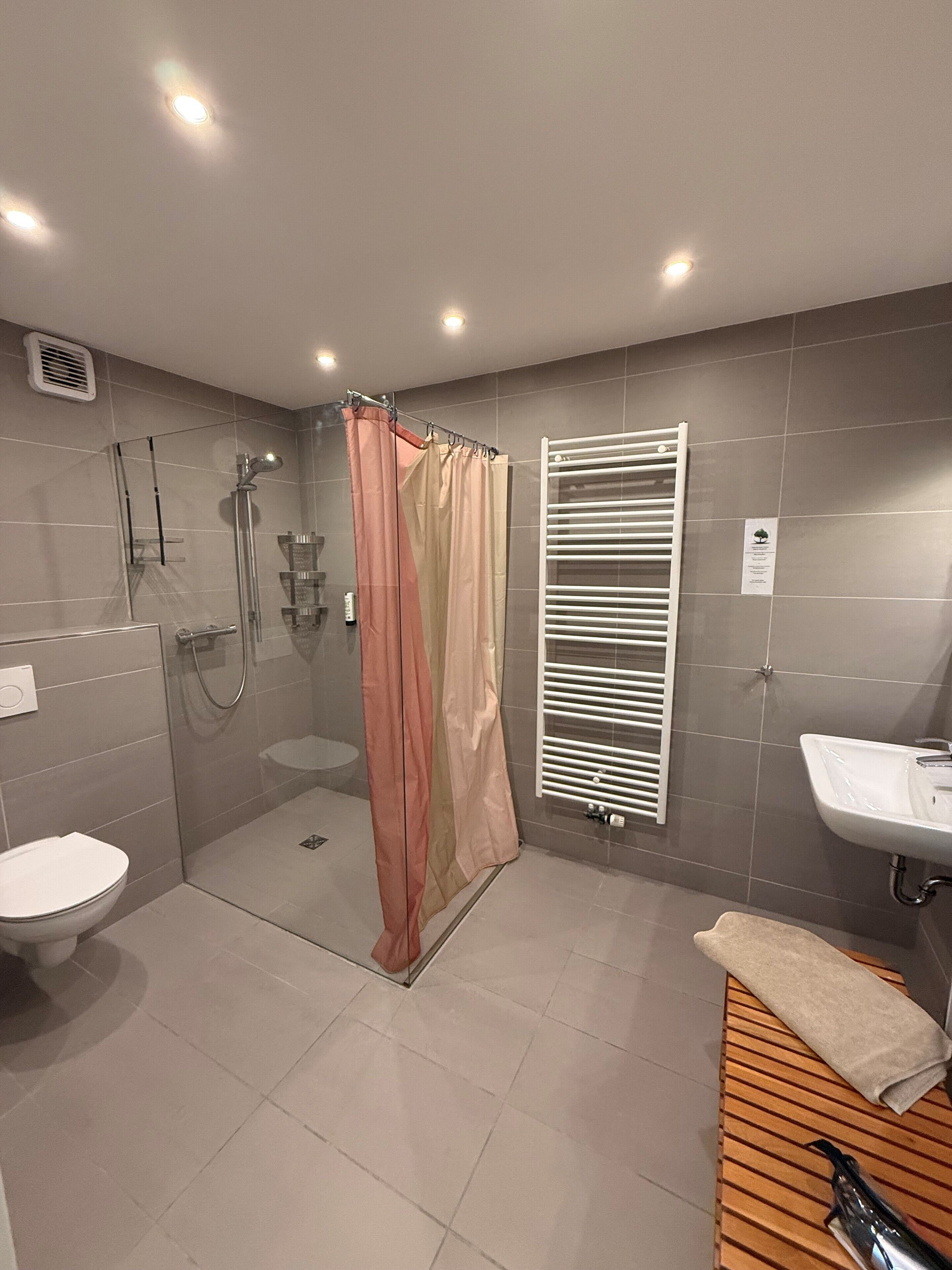 A modern bathroom with a glass-enclosed shower, a white sink, and a towel rack.