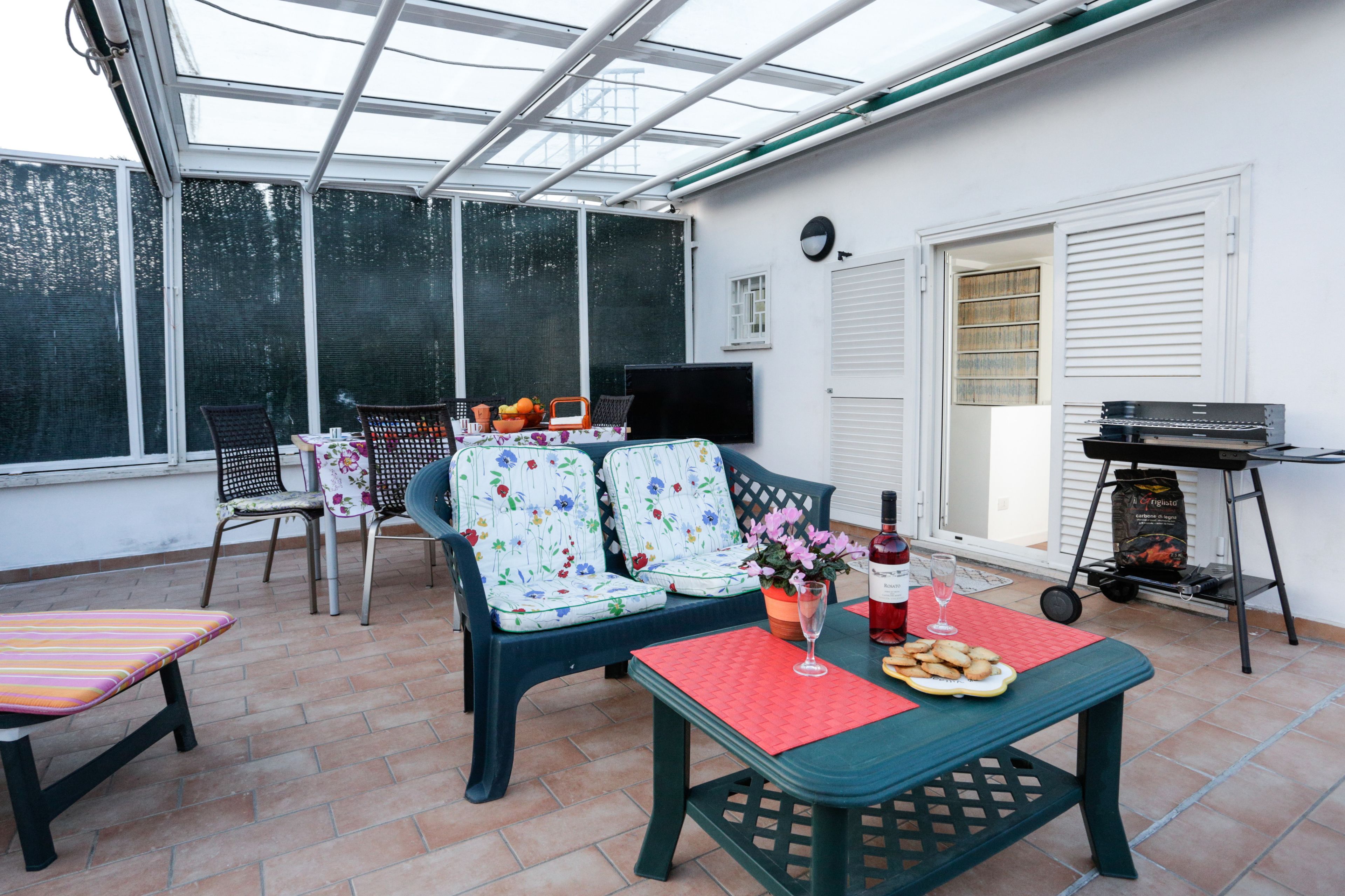 A covered patio with a table, chairs, a sofa, and a grill.