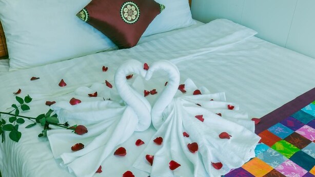 A bed with white linens, a decorative pillow, and a quilt with a colorful pattern. - Sapa Center View Hotel (Sa Pa)