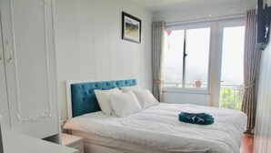 A bedroom with a bed, a dresser, a window with curtains, and a framed picture on the wall. - Sapa Center View Hotel (Sa Pa)