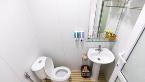 A small, compact bathroom with a toilet, sink, and hand soap dispensers. - Sapa Center View Hotel (Sa Pa)