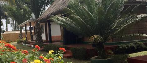 Un edificio con techo de paja y un jardín delantero.